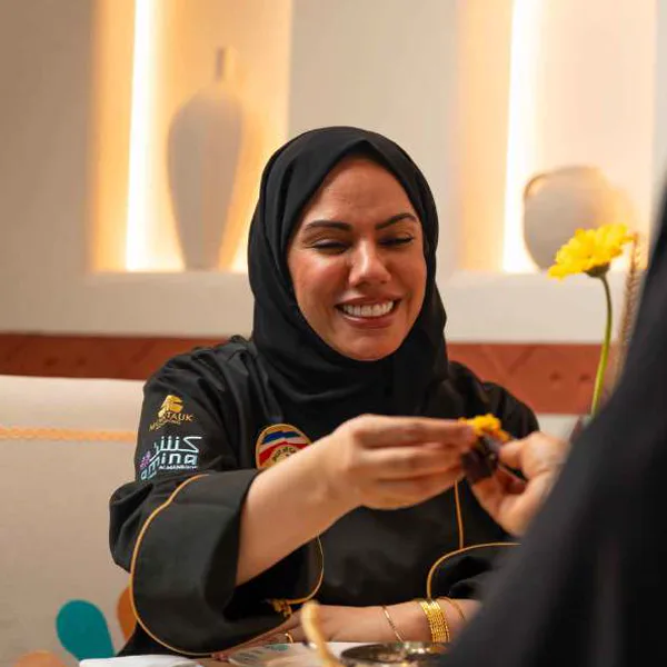 Chef Mariam Al Mansoori laughing at the table, a yellow flower beside her