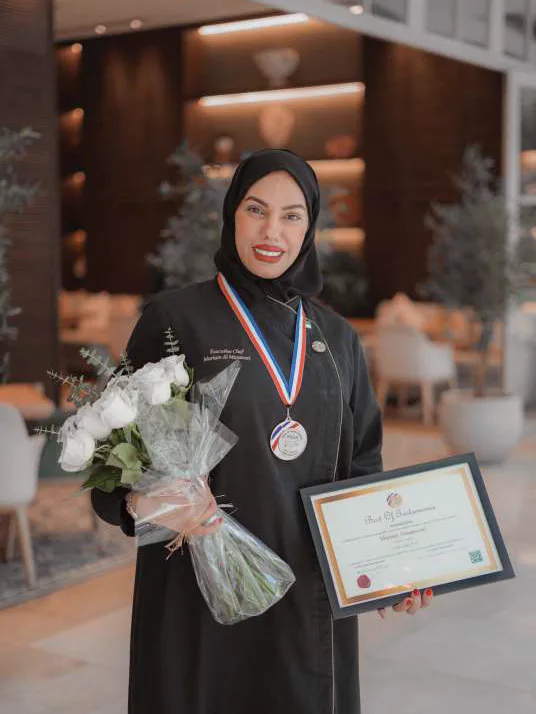 Chef Mariam Al Mansoori with the Golden Chef medal, her certificate and a bouquet